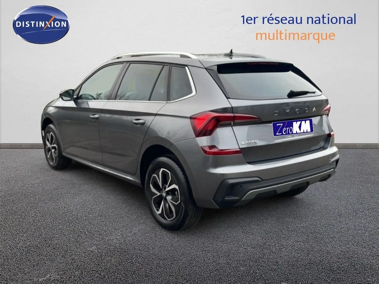 Vue 3/4 arrière droite d'un Skoda Kamiq gris graphite avec jantes alliage et toit ouvrant, sur fond neutre.