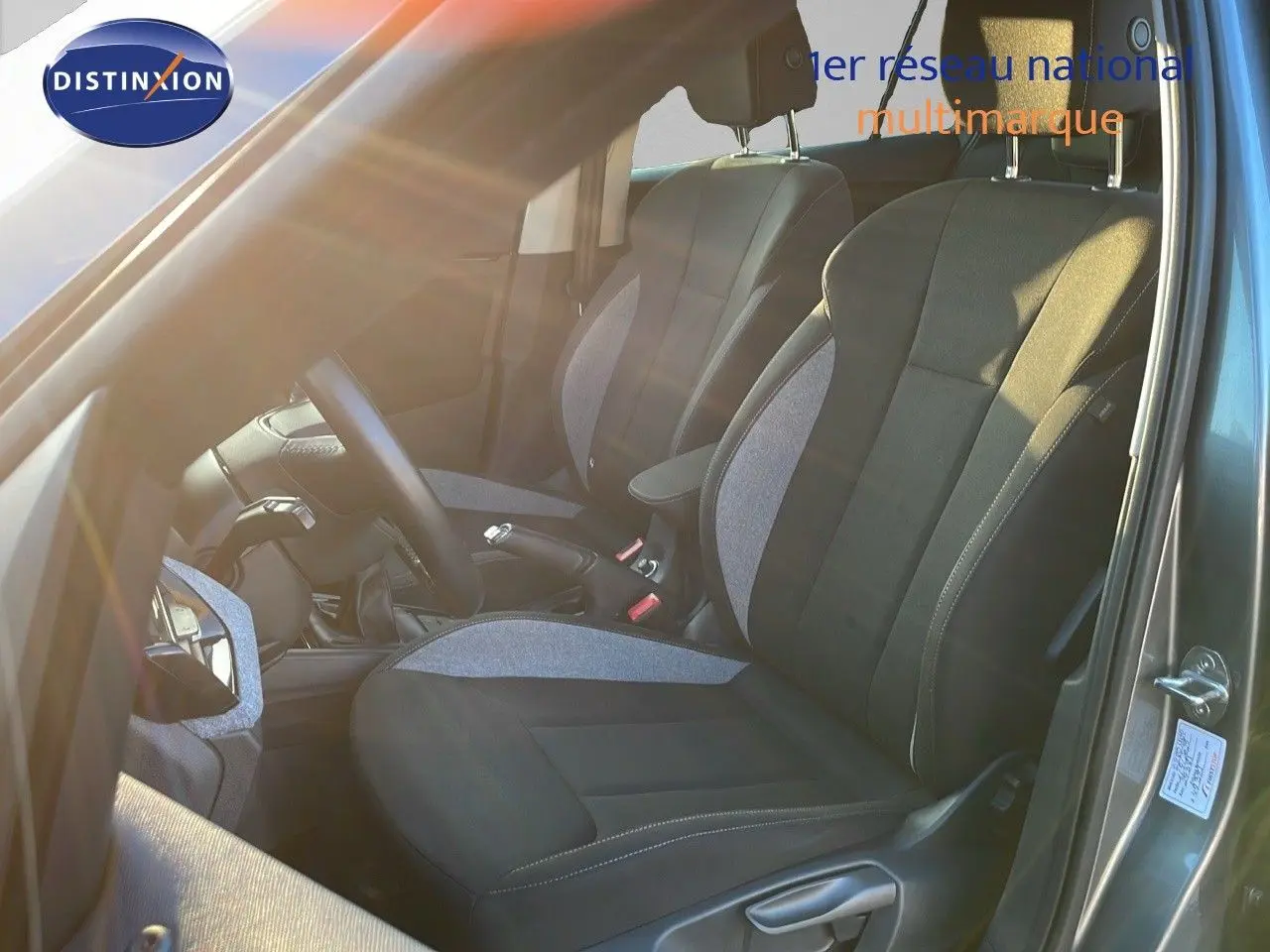 Vue intérieure côté conducteur du Skoda Kamiq gris graphite métal 2024, montrant les sièges avant en tissu bicolore et le levier de vitesses manuel.