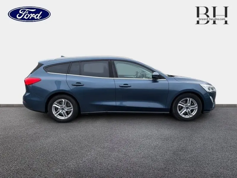 Profil droit de la Ford Focus SW 1.5 EcoBlue bleu azur métallisé avec jantes alu et vitres teintées.