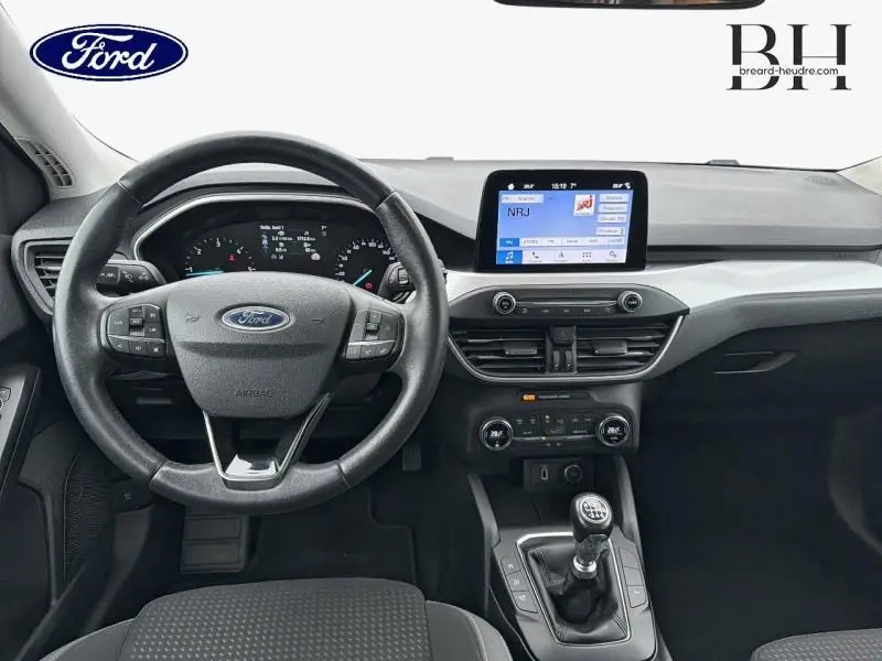 Vue intérieure avant du Ford Focus SW 2019, tableau de bord noir avec volant cuir multifonction et écran tactile central.