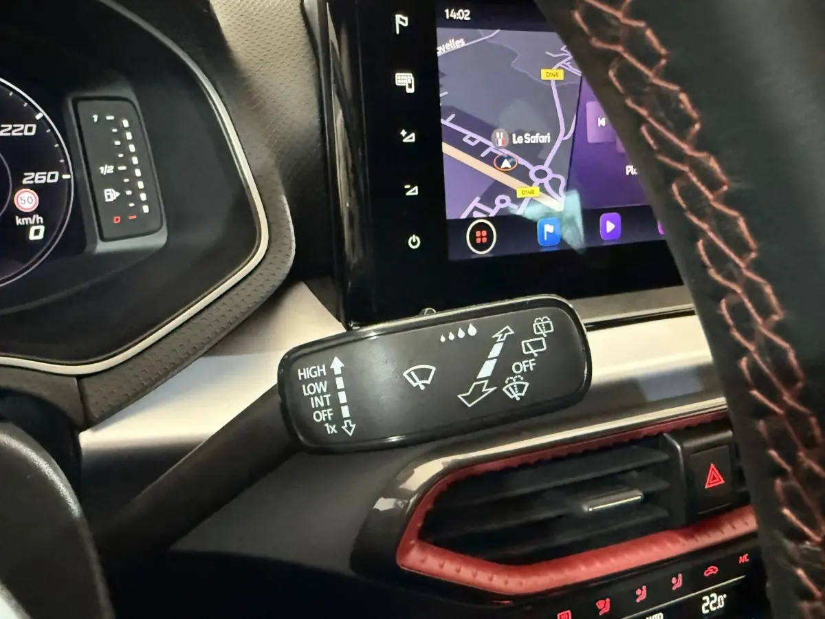 Gros plan sur la commande d’essuie-glace à gauche du volant cuir avec surpiqûres rouges dans une SEAT Ibiza blanche 2024.