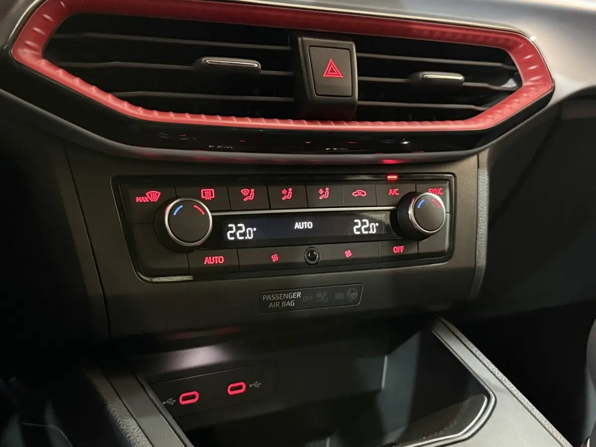 Détail de la console centrale de la SEAT Ibiza blanche 2024, avec commandes de climatisation et éclairage rouge.