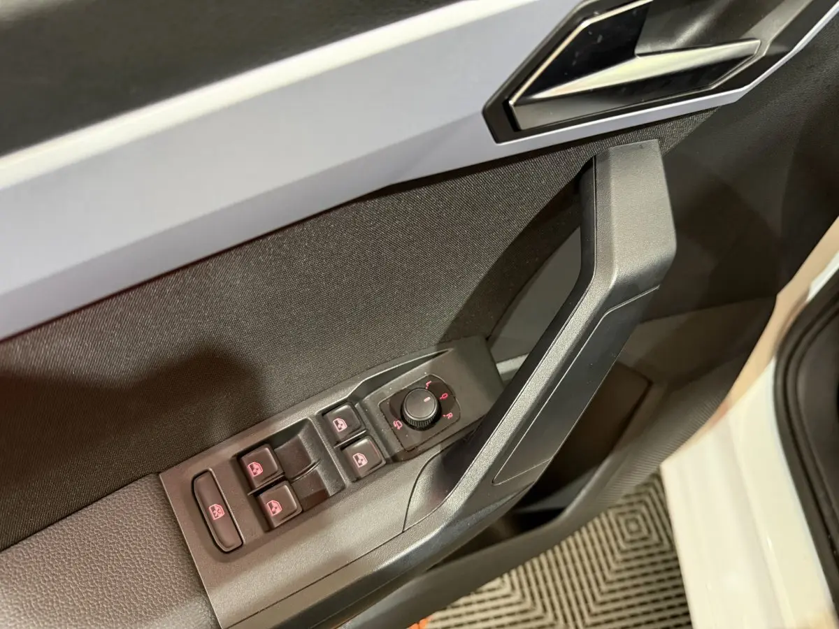 Détail de la commande des vitres et rétroviseurs côté conducteur sur porte intérieure noire d’une SEAT Ibiza blanche 2024.