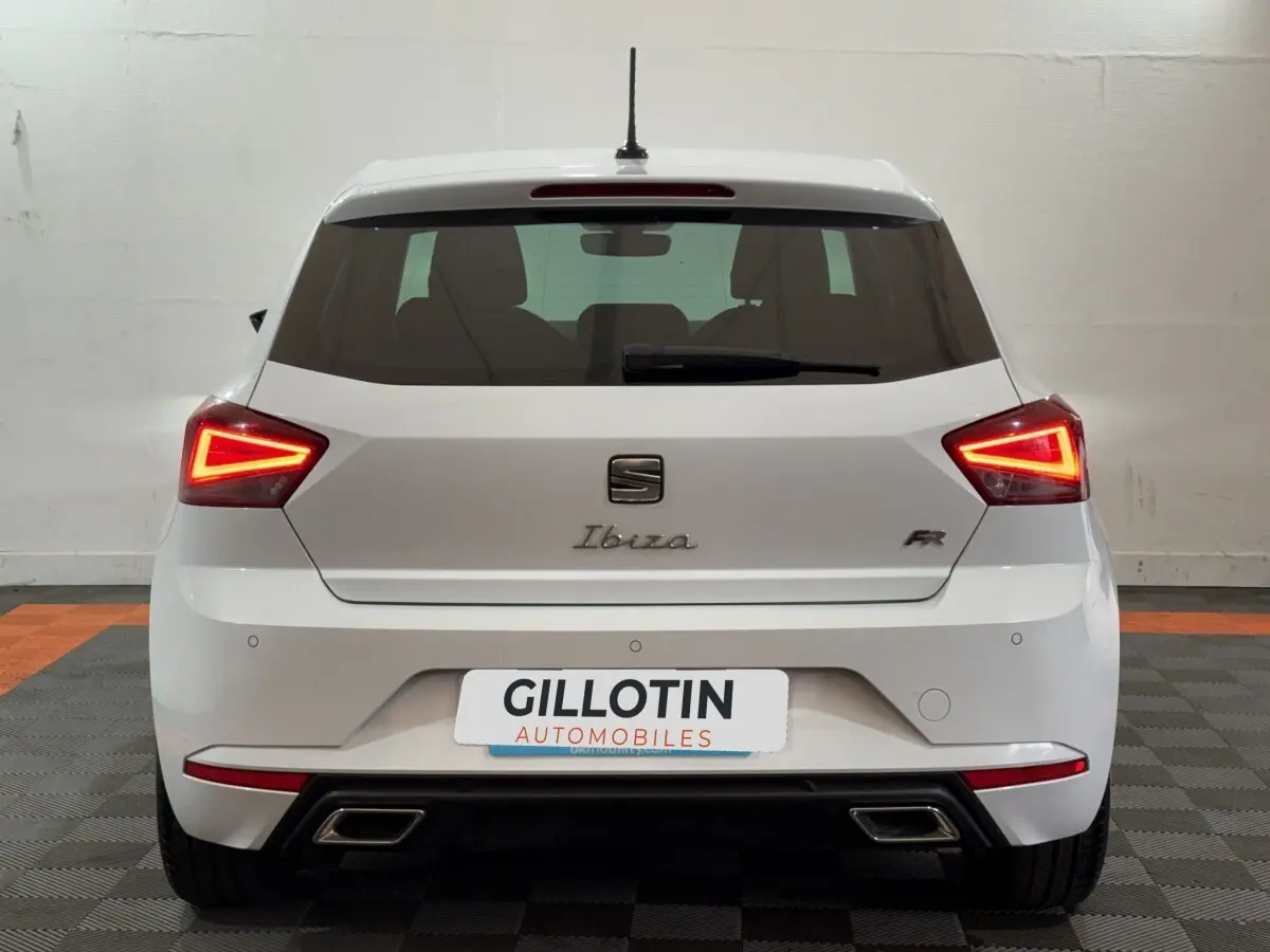 Vue arrière d'une SEAT Ibiza 1.0 TSI 110 FR blanche avec feux LED triangulaires et doubles sorties d'échappement.