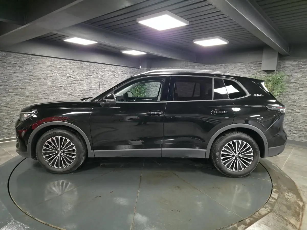 Vue de profil côté gauche du Volkswagen Tiguan noir 2025 avec jantes alliage 18 pouces et toit ouvrant.