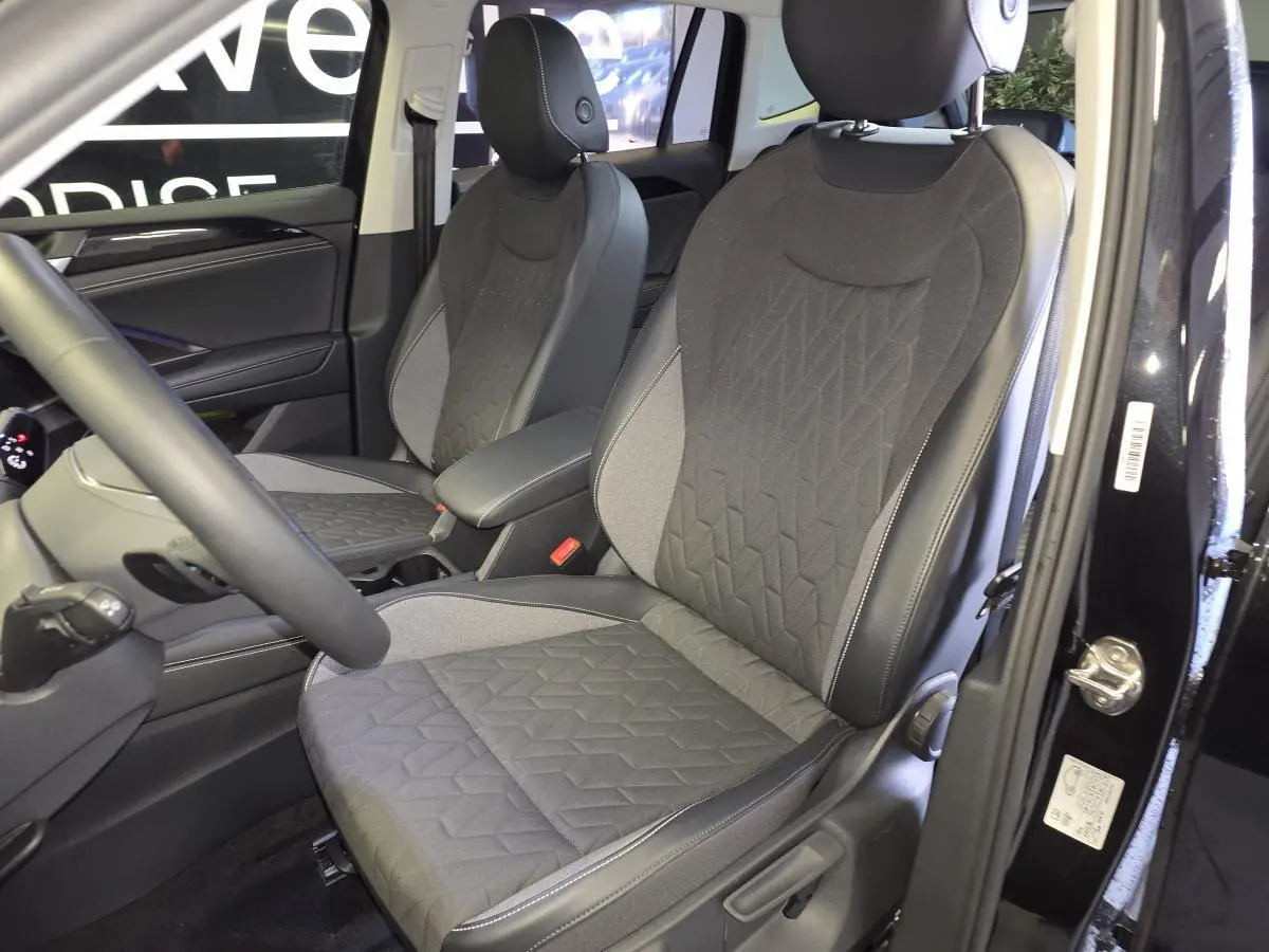 Vue intérieure côté avant droit du Volkswagen Tiguan 2025 noir, sièges tissu gris avec surpiqûres géométriques.