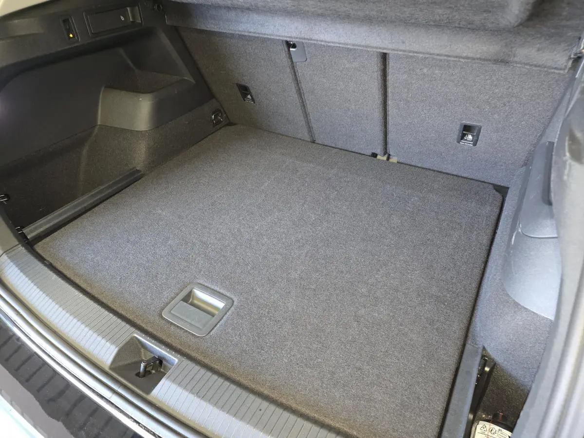 Coffre spacieux vu de dessus du Volkswagen Tiguan noir 2025 avec revêtement gris et crochet d'attelage escamotable.