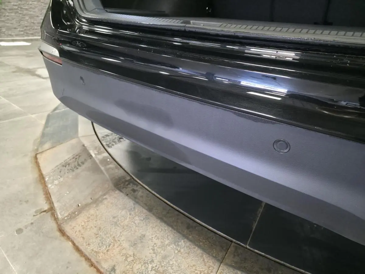 Vue rapprochée du pare-chocs arrière noir du Volkswagen Tiguan 2025 avec capteurs de stationnement intégrés.