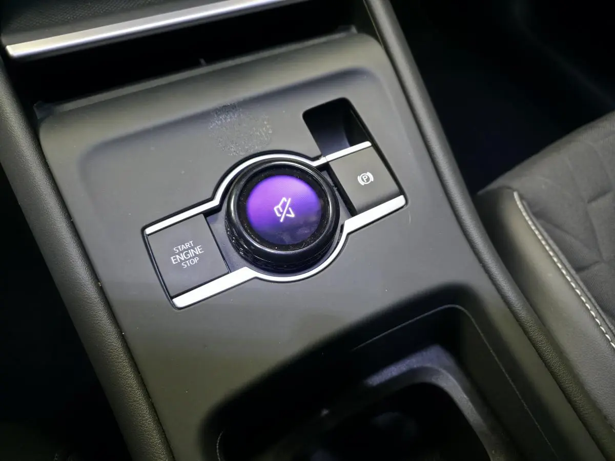 Gros plan sur la console centrale du Volkswagen Tiguan 2025, bouton rotatif violet et commandes de démarrage et frein à main.