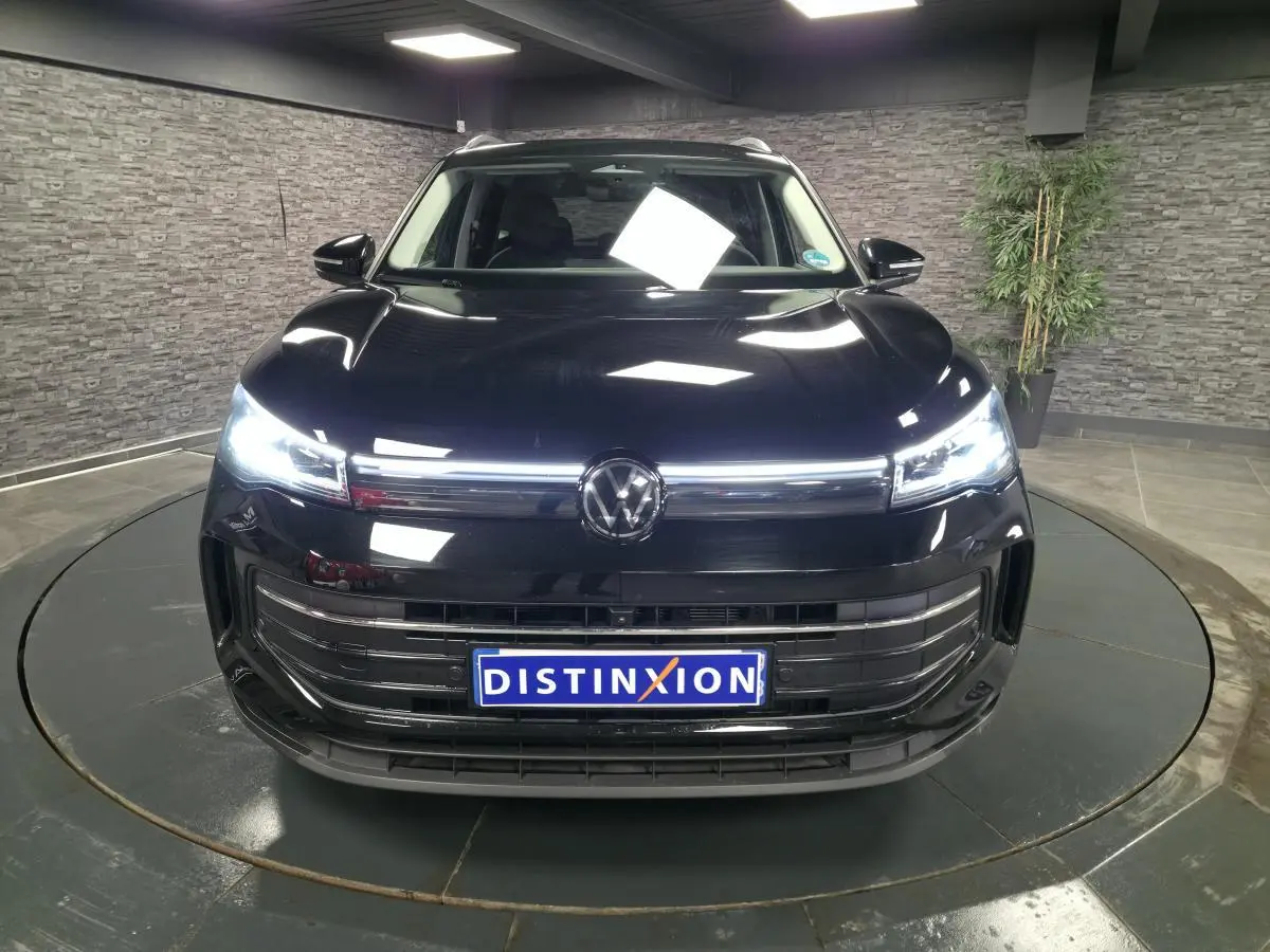 Vue avant du Volkswagen Tiguan noir 2025 avec phares LED allumés et calandre chromée distinctive.