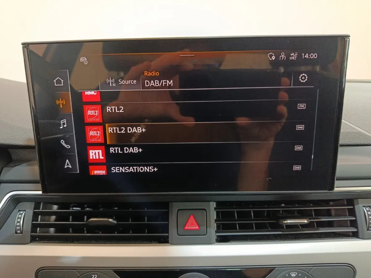 Écran tactile central de l’Audi A4 35 TFSI Business Line 2024 affichant les stations radio DAB/FM, intérieur noir.