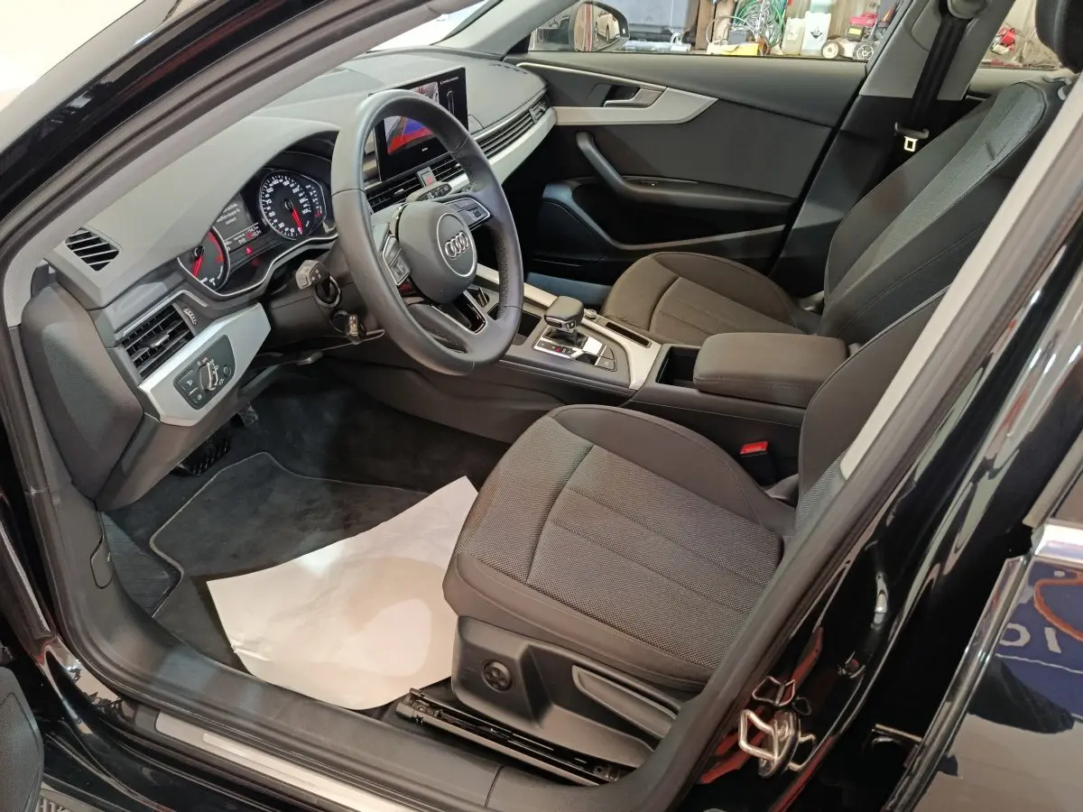 Vue intérieure côté conducteur de l'Audi A4 35 TFSI 2024 noire, avec tableau de bord numérique et sièges tissu gris.