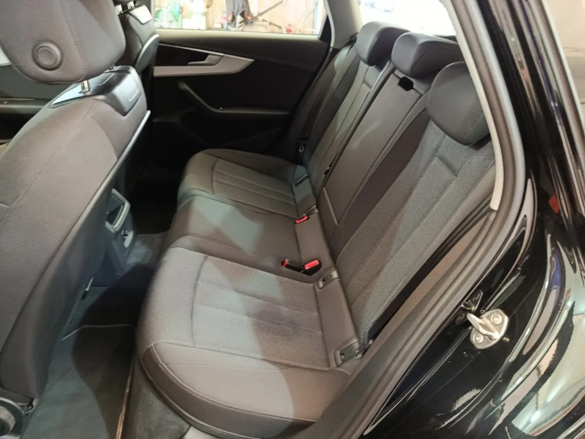 Vue côté droit de la banquette arrière noire de l'Audi A4 35 TFSI 2024 avec sièges tissu et ceintures visibles.
