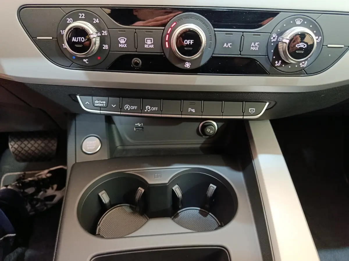 Vue rapprochée du tableau de bord et console centrale noire de l'Audi A4 35 TFSI 2024 avec commandes climatisation et boutons fonctionnels.