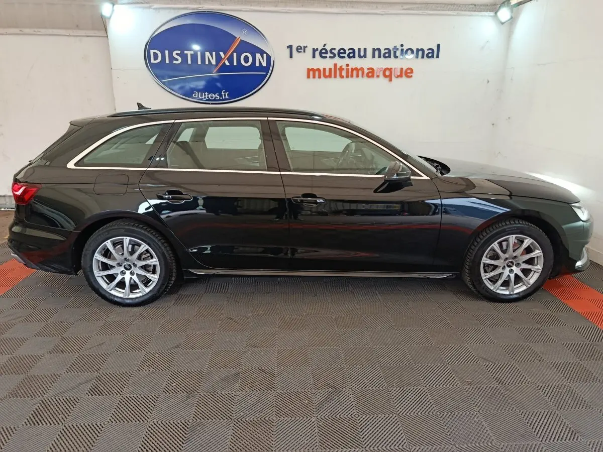 Audi A4 35 TFSI Business Line noire vue de profil côté droit dans un showroom avec logo Distinxion en arrière-plan.