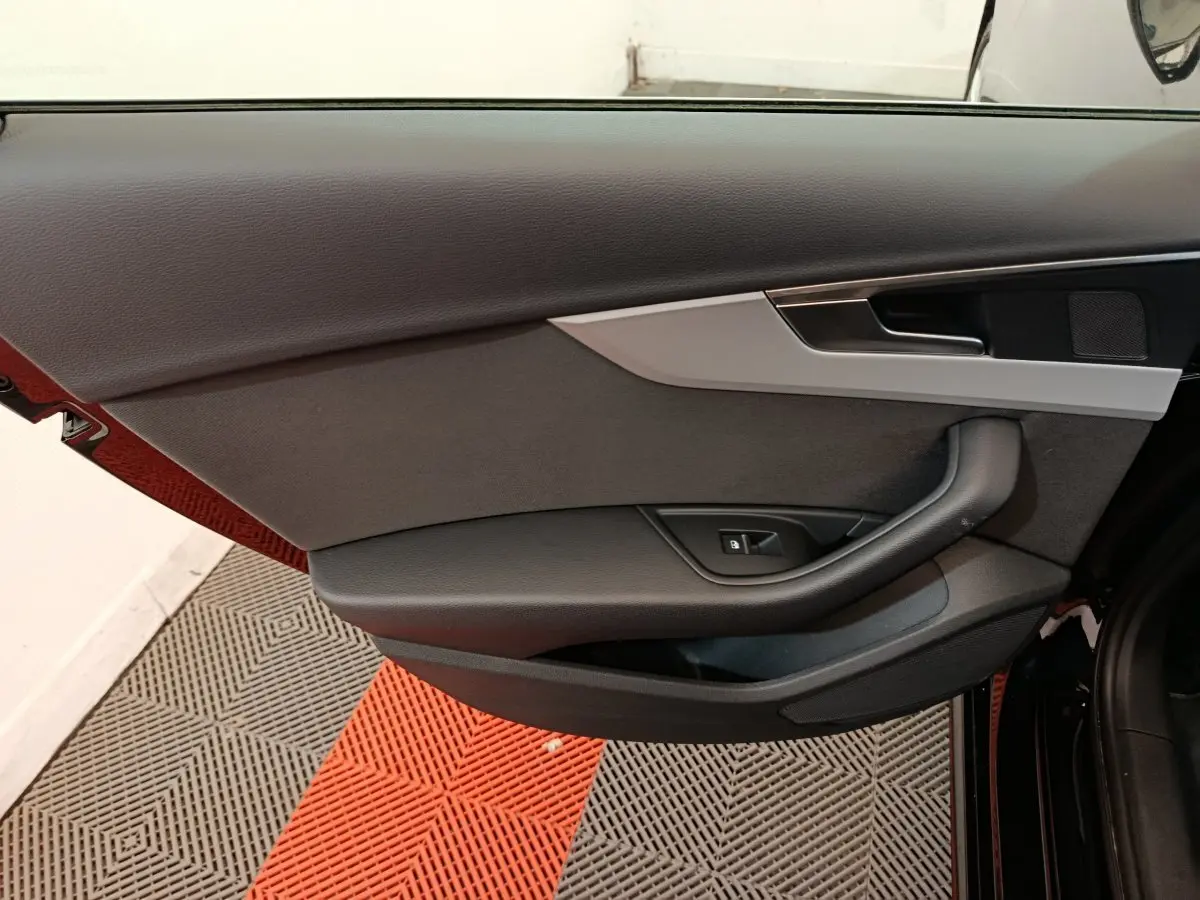 Vue du panneau de porte côté gauche de l'Audi A4 35 TFSI noir, avec poignée et commande de vitre électrique.