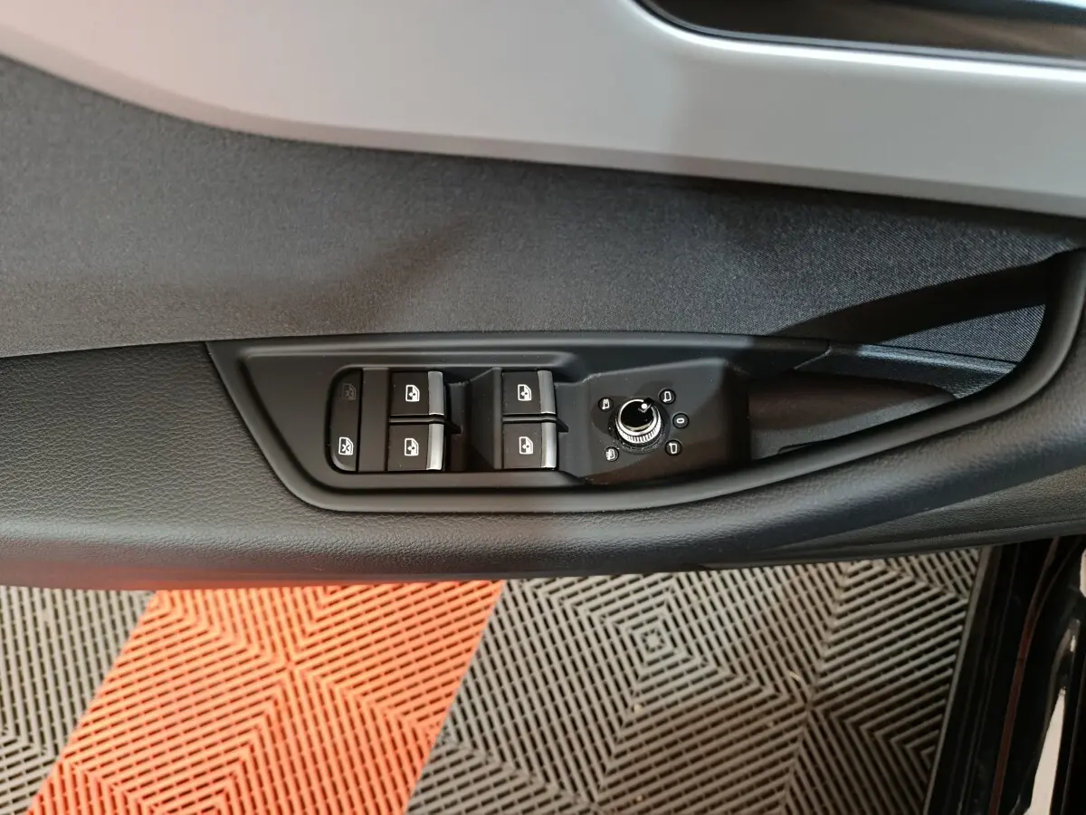 Vue rapprochée du panneau de commandes des vitres et rétroviseurs côté gauche d’une Audi A4 noire 2024.