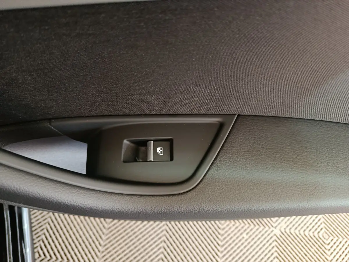 Détail du bouton de lève-vitre noir sur la porte intérieure côté gauche d'une Audi A4 35 TFSI 2024 noire.
