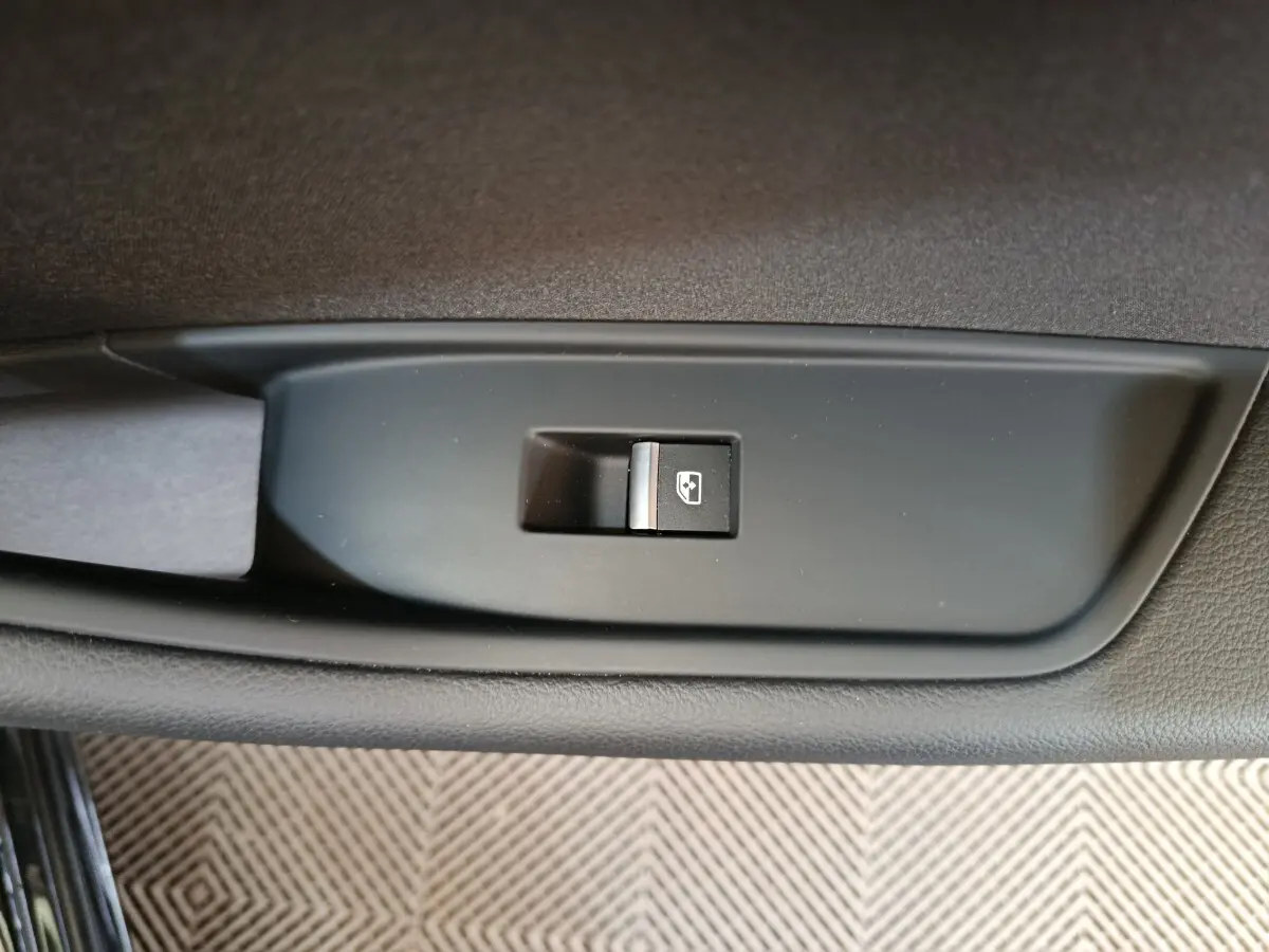 Gros plan sur l'interrupteur de lève-vitre côté gauche de l'Audi A4 noire 2024, finition Business Line.