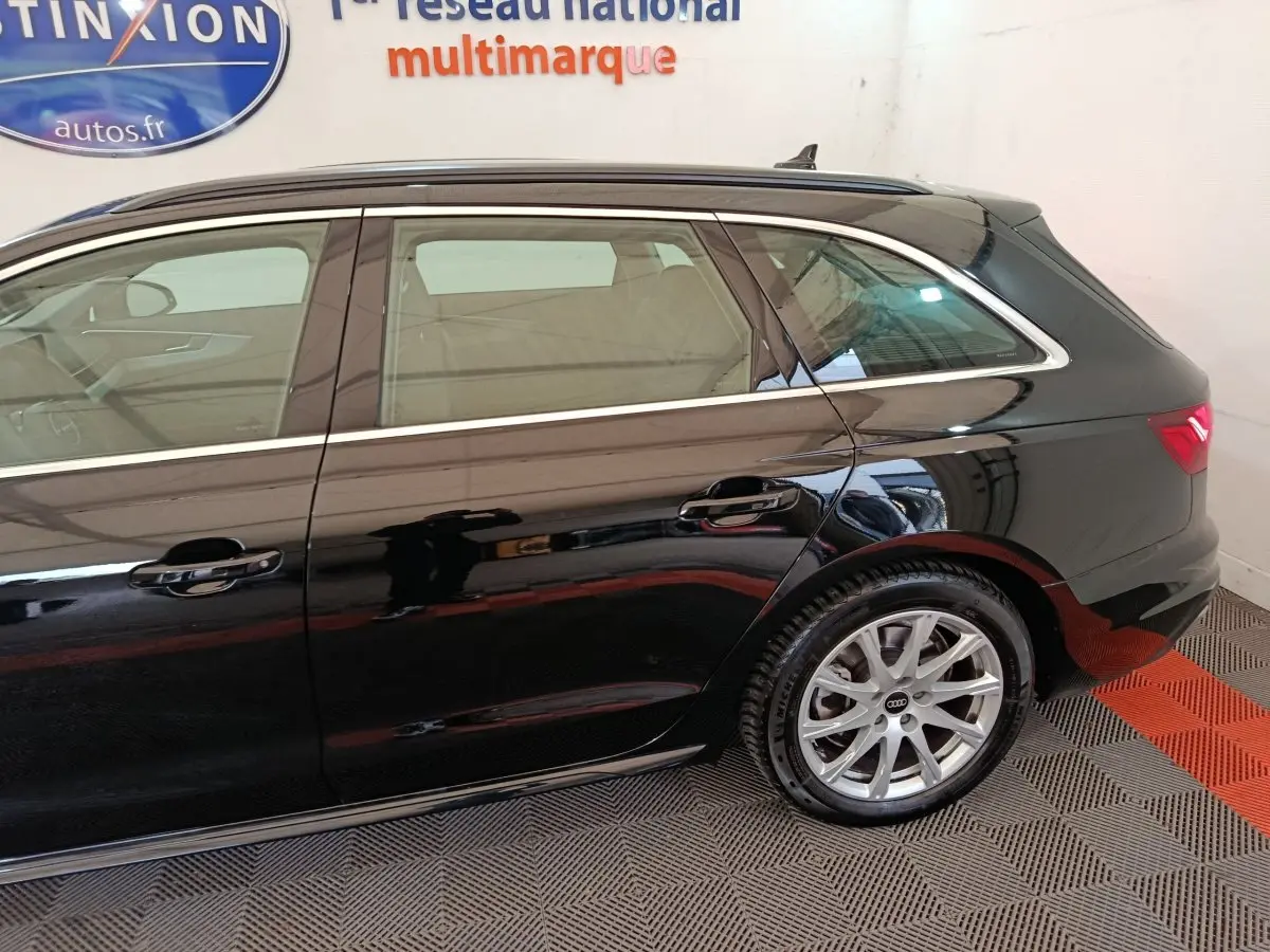 Vue latérale droite d'une Audi A4 noire 2024 avec jantes alliage et lignes chromées autour des fenêtres.