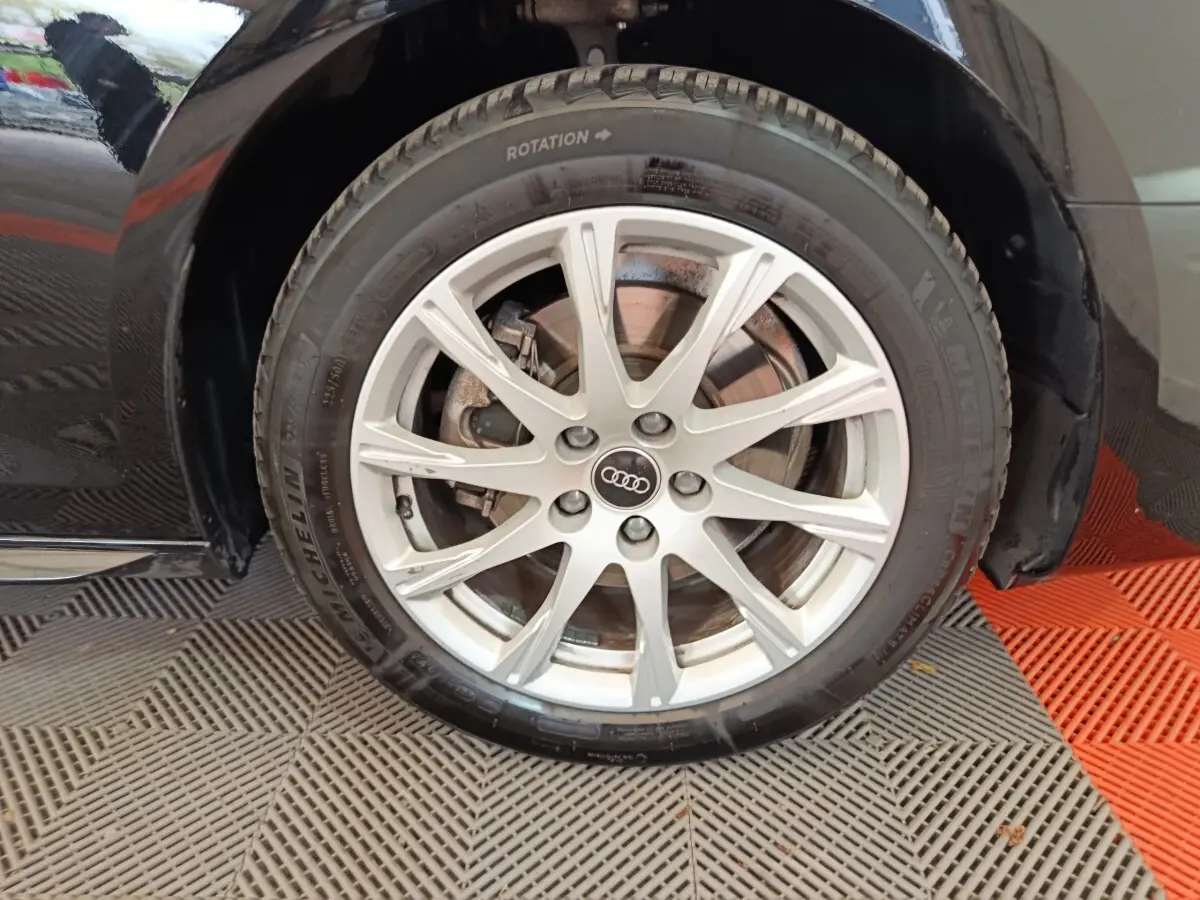 Gros plan sur la roue avant droite noire d'une Audi A4 35 TFSI 150 S tronic Business Line avec jante argentée multi-branches.