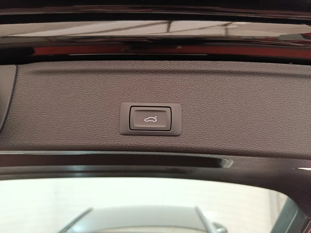 Bouton d'ouverture électrique du coffre sur la partie intérieure du hayon noir d'une Audi A4 35 TFSI 2024.