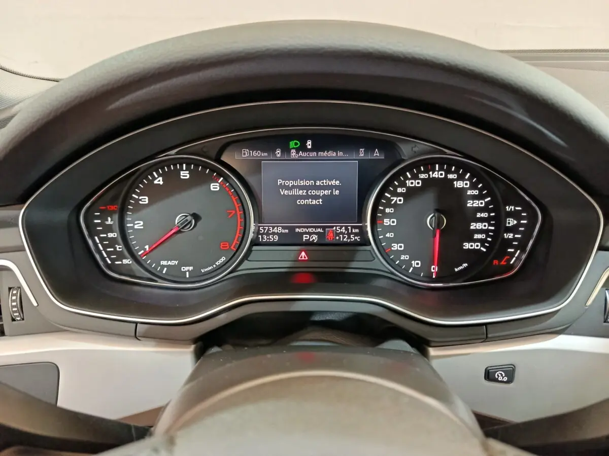 Vue rapprochée du tableau de bord numérique d'une Audi A4 35 TFSI 2024, affichage des compteurs et message d'arrêt.
