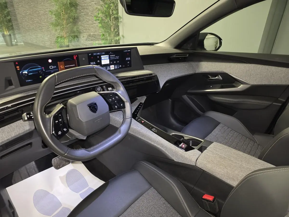 Vue intérieure côté conducteur du Peugeot 3008 gris 2025, avec tableau de bord numérique et sellerie tissu gris chiné.