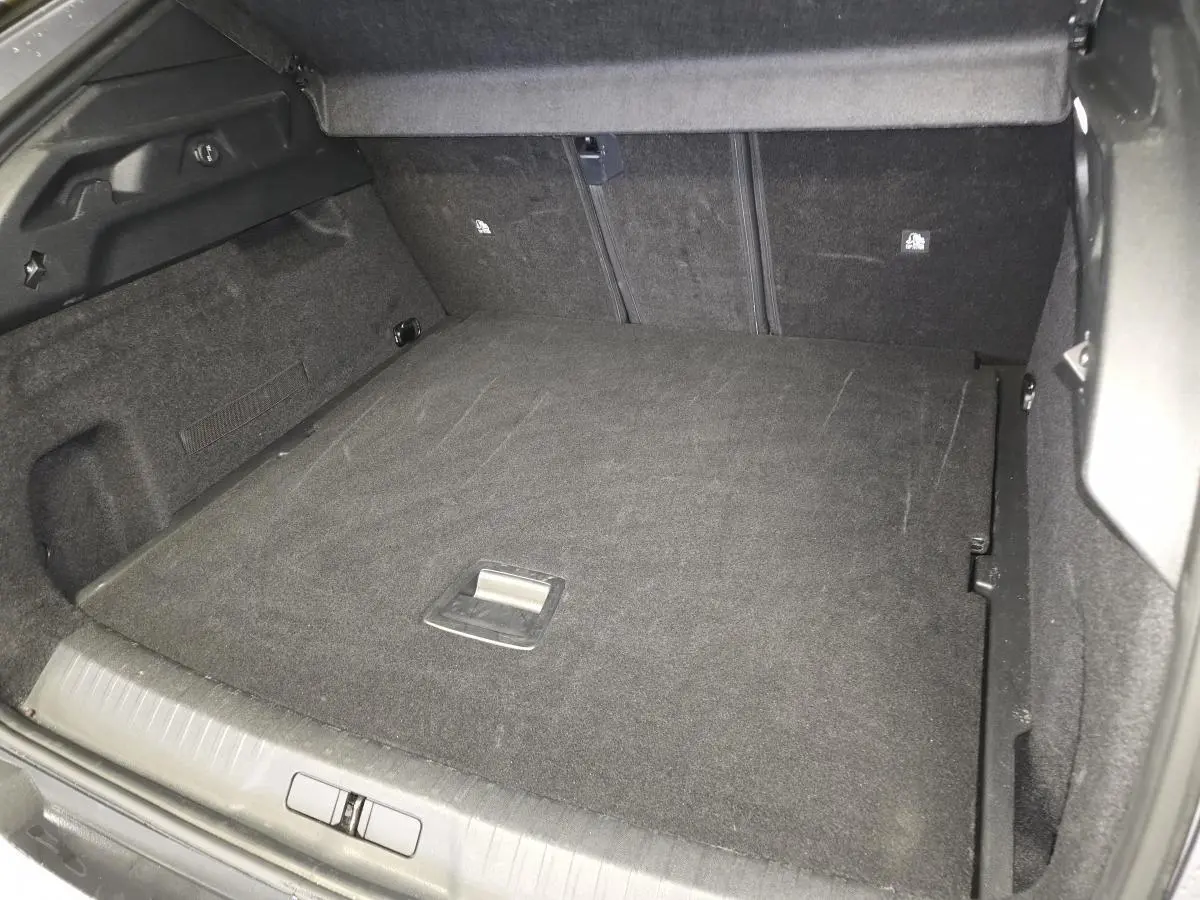Coffre spacieux du Peugeot 3008 gris, vue intérieure montrant le plancher plat et les dossiers arrière rabattus.