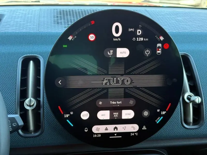 Vue rapprochée du tableau de bord circulaire digital du MINI Countryman 2024, affichage de la climatisation et vitesse.
