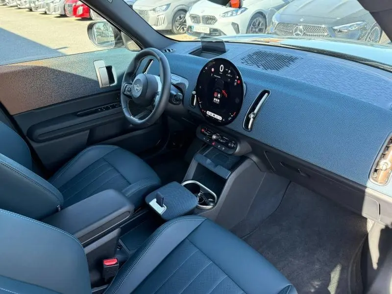 Vue intérieure côté conducteur du MINI Countryman 2024 noir Midnight Black II, avec tableau de bord moderne et écran circulaire central.