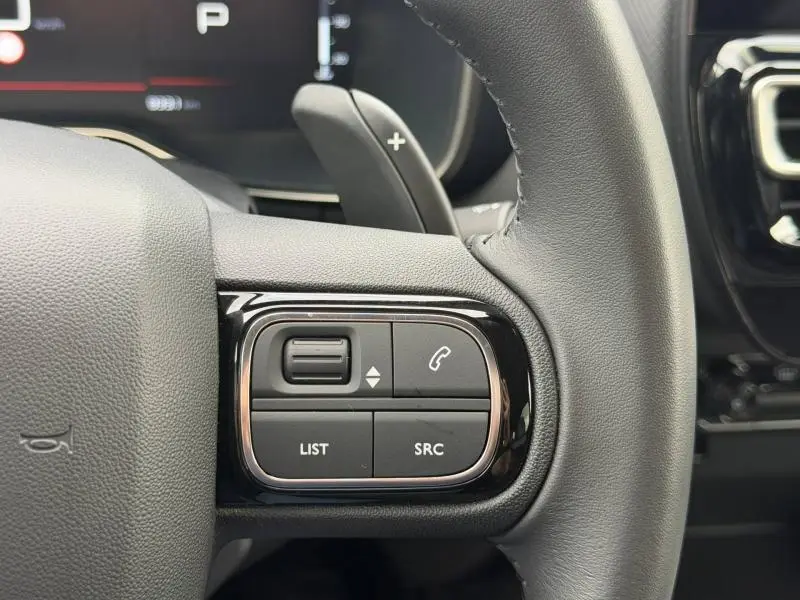 Gros plan sur les commandes gauche du volant cuir noir du Citroën C5 Aircross 2024 Hybride, avec touches multifonctions.