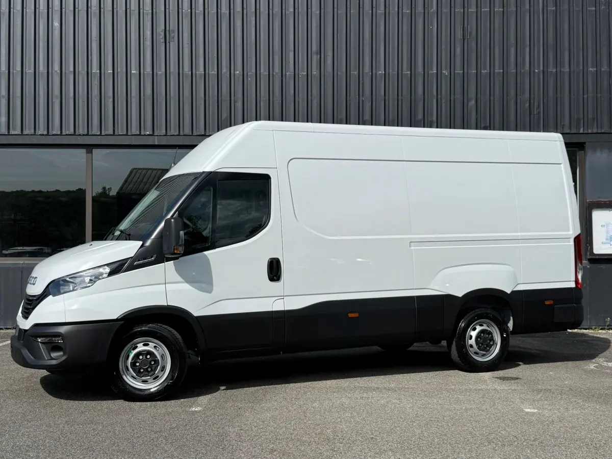 Fourgon Iveco Daily blanc vu de profil côté gauche, soulignant sa silhouette haute et ses détails noirs bas de caisse.