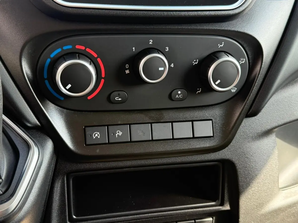 Détail du tableau de bord du Iveco Daily 2026 montrant les commandes de climatisation et les boutons de fonction en plastique noir.