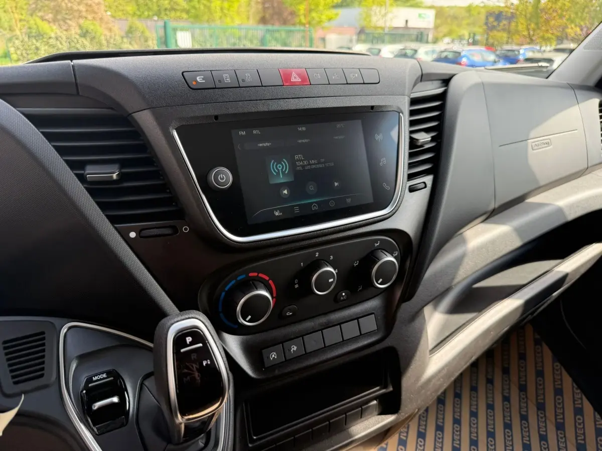Vue intérieure du tableau de bord de l'Iveco Daily 2026, avec écran tactile, commandes climatisation et levier de boîte automatique.