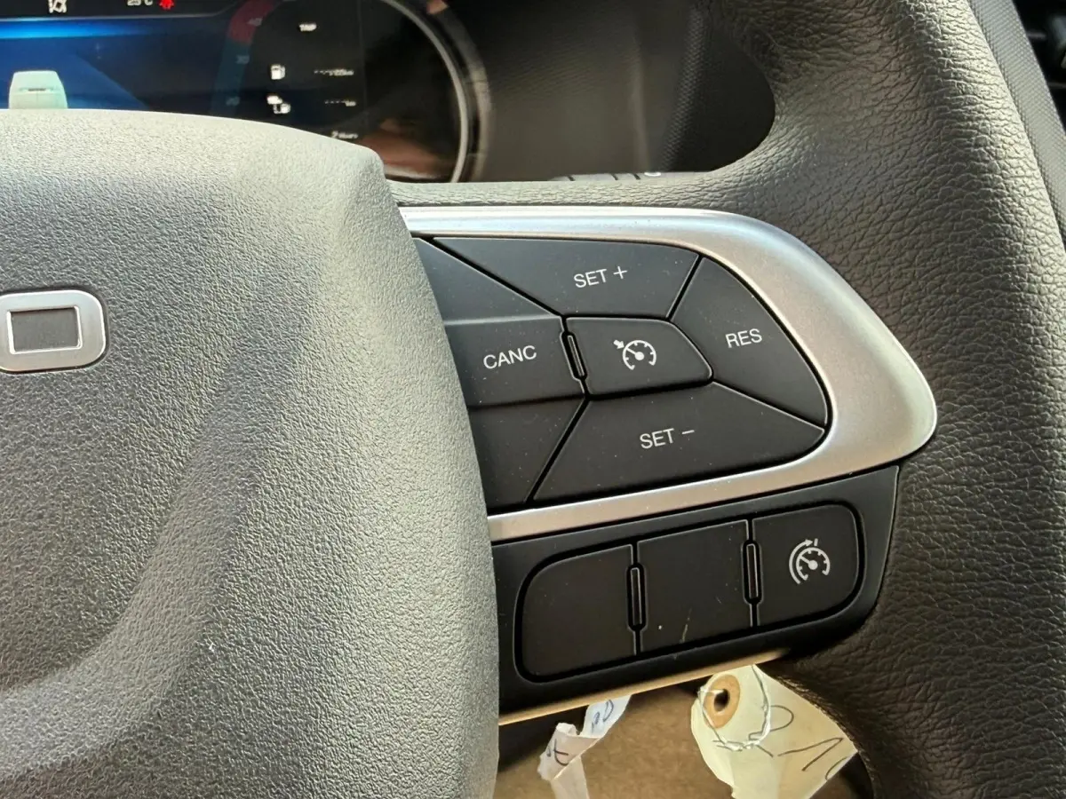 Gros plan sur les commandes de régulateur de vitesse au volant noir du Iveco Daily blanc 2026, côté droit.