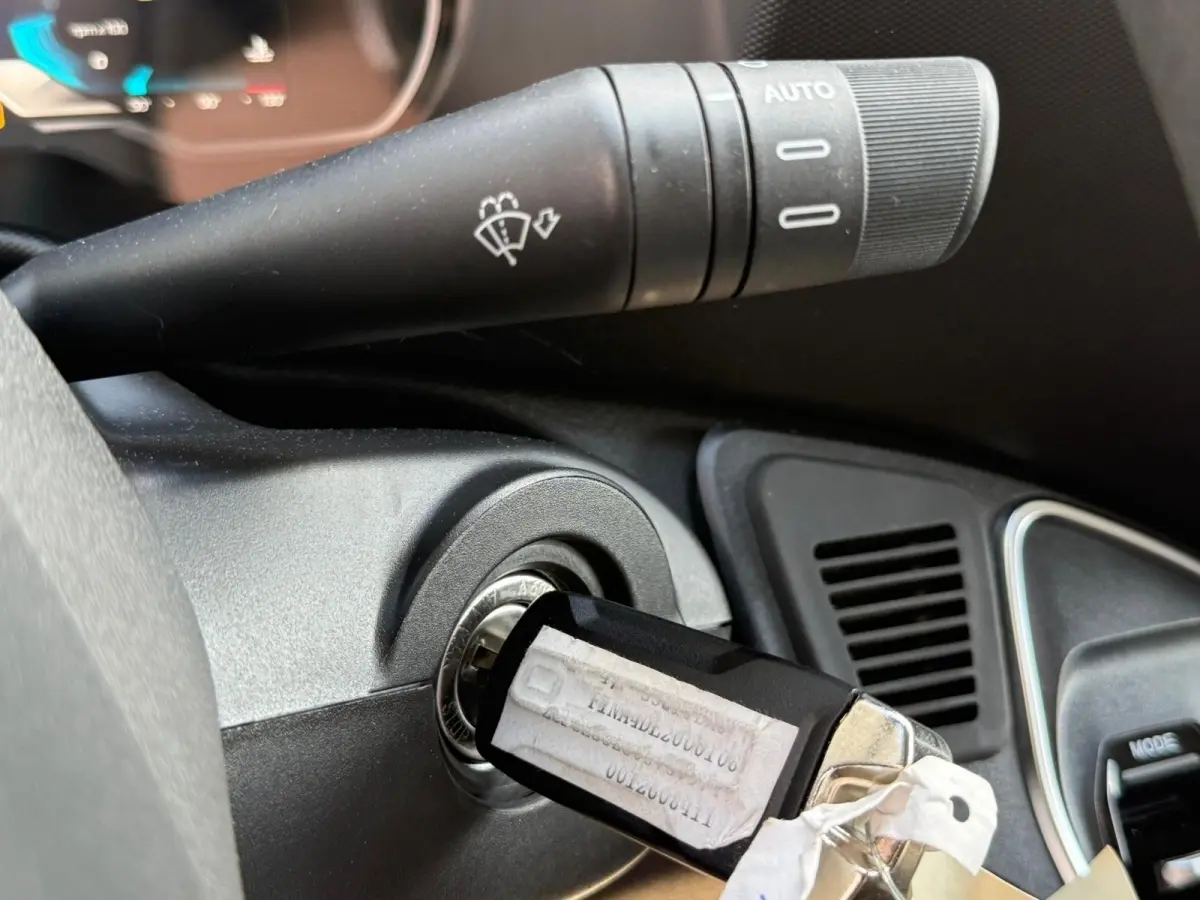 Gros plan sur la clé insérée dans le contact d'un Iveco Daily 2.3 blanc, avec commande d'essuie-glace visible.