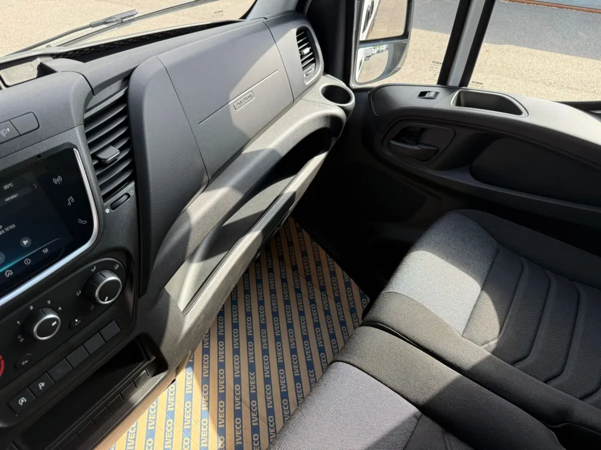 Vue intérieure côté passager du tableau de bord gris et siège tissu noir du fourgon Iveco Daily 2.3 blanc 2026.