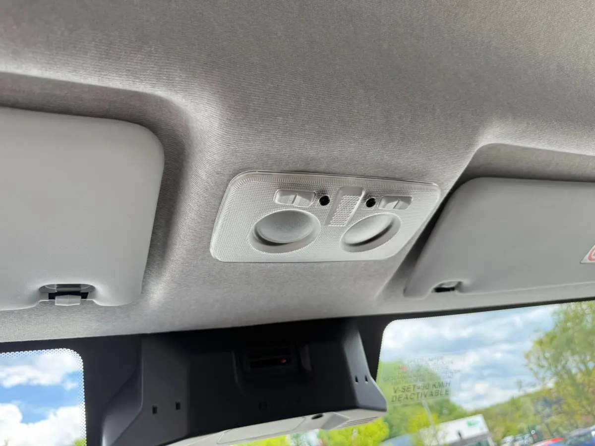 Vue intérieure du plafond avant du fourgon Iveco Daily blanc 2026, montrant les plafonniers et pare-soleils.