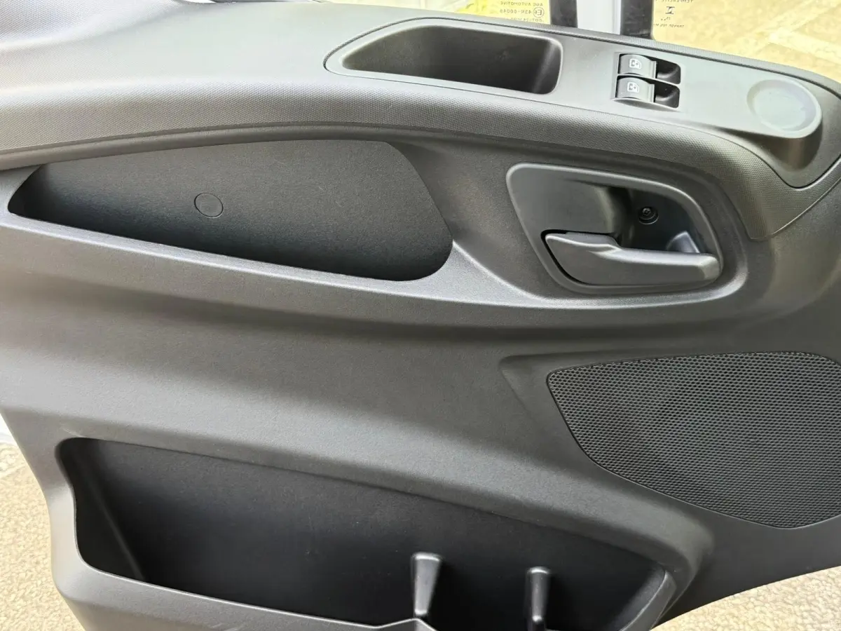 Intérieur de la porte côté conducteur du Iveco Daily blanc 2026, avec poignée, commandes de vitre et haut-parleur intégrés.