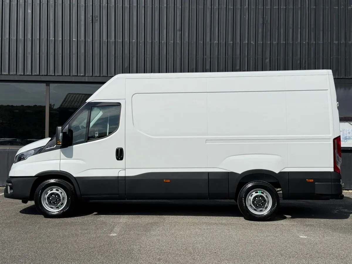 Fourgon Iveco Daily blanc vu de profil côté gauche, avec bas de caisse noir et grande surface lisse sans fenêtres.