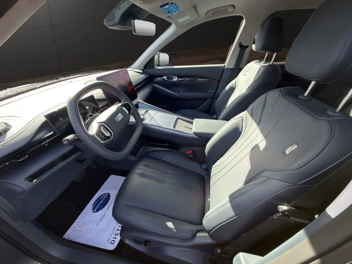 Intérieur avant droit du Geely E5 gris foncé 2026, sièges cuir noirs et tableau de bord avec écran tactile central.