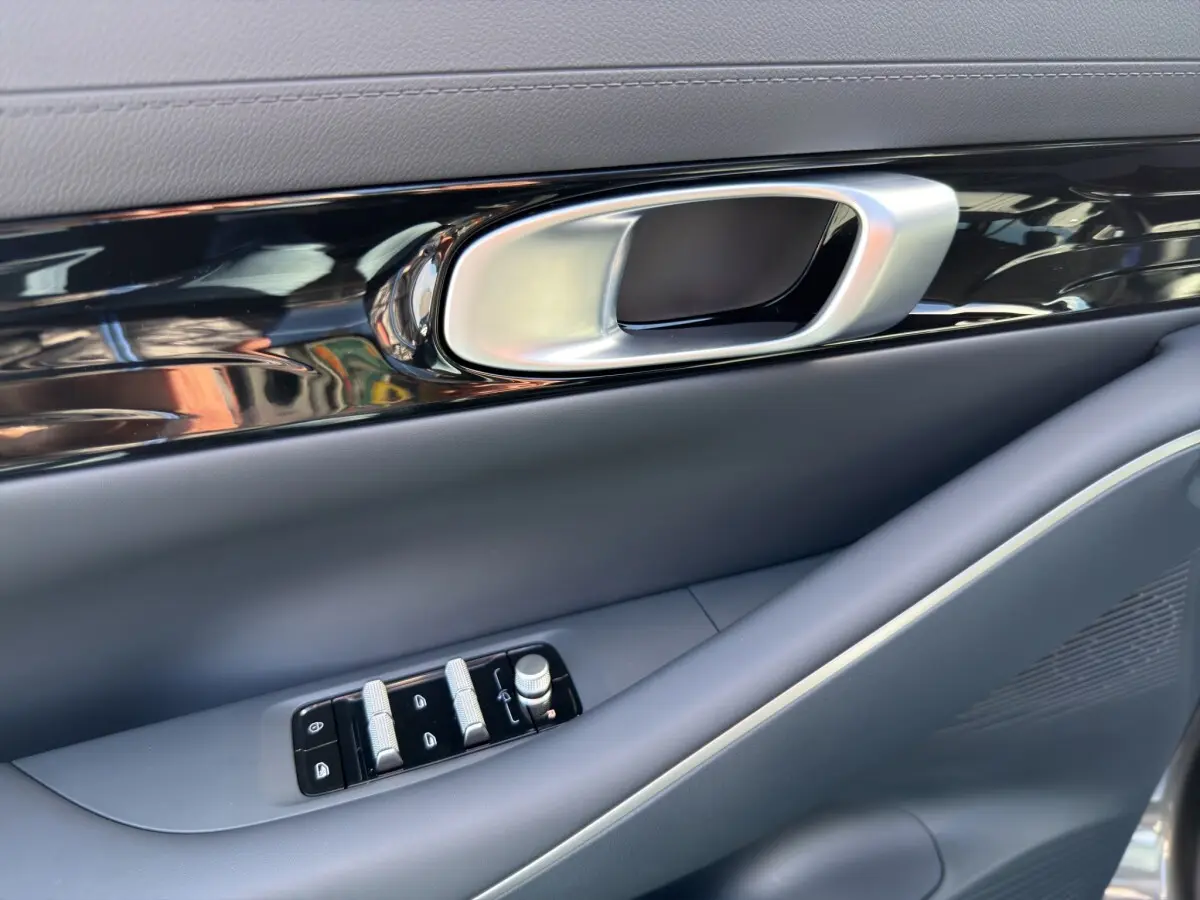 Détail de la poignée intérieure et des commandes de fenêtre côté conducteur du Geely E5 gris foncé 2026.