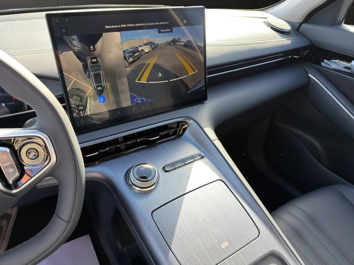 Vue intérieure du tableau de bord et console centrale du Geely E5 gris foncé, avec écran tactile affichant la caméra de recul.