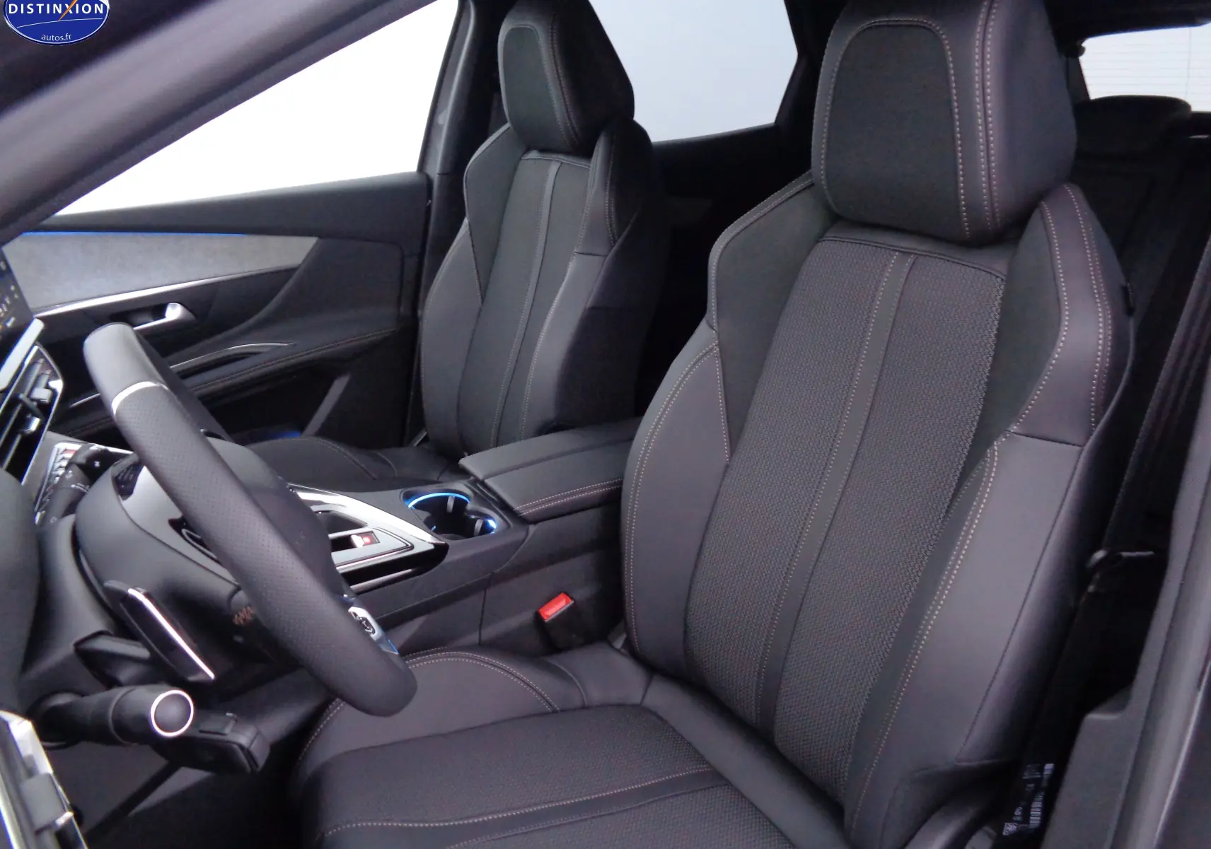 Vue intérieure côté conducteur du Peugeot 3008 2023, sièges en cuir noir avec surpiqûres contrastées et console centrale moderne.