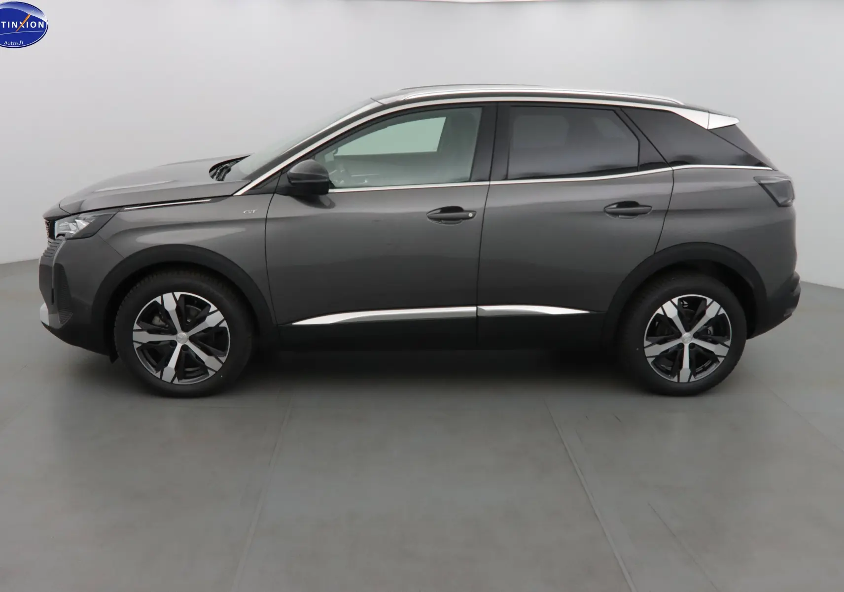 Profil côté gauche du Peugeot 3008 GT 2023 en gris platinium métallisé avec jantes bi-ton et toit contrasté blanc.