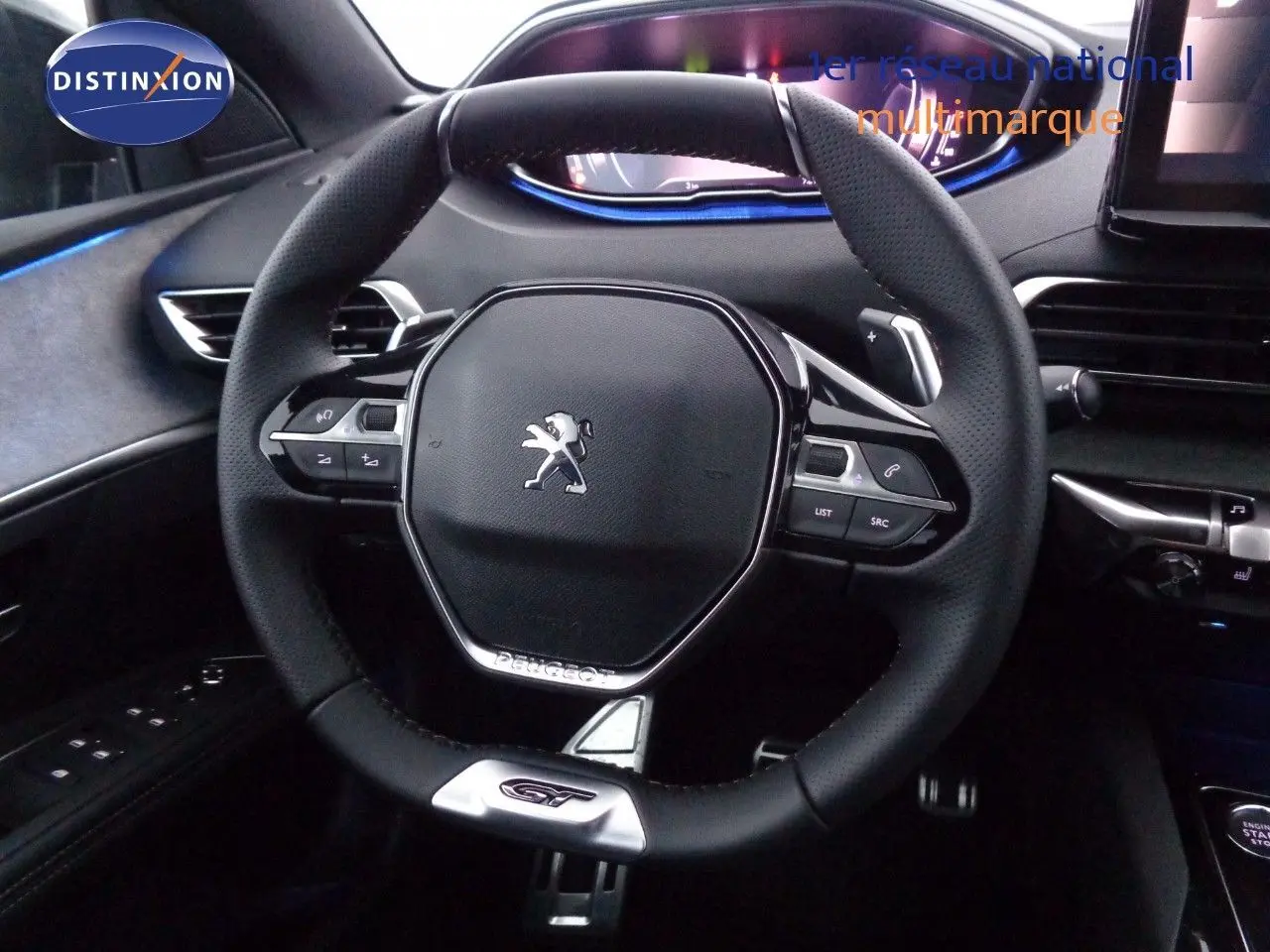 Vue rapprochée du volant cuir noir avec logo Peugeot et badge GT du Peugeot 3008 2023, intérieur moderne et éclairage bleu.