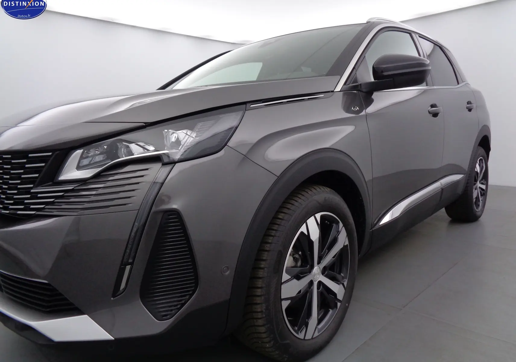 Vue 3/4 avant droit d'un Peugeot 3008 gris platinium métal avec jantes alliage bicolores et calandre distinctive.