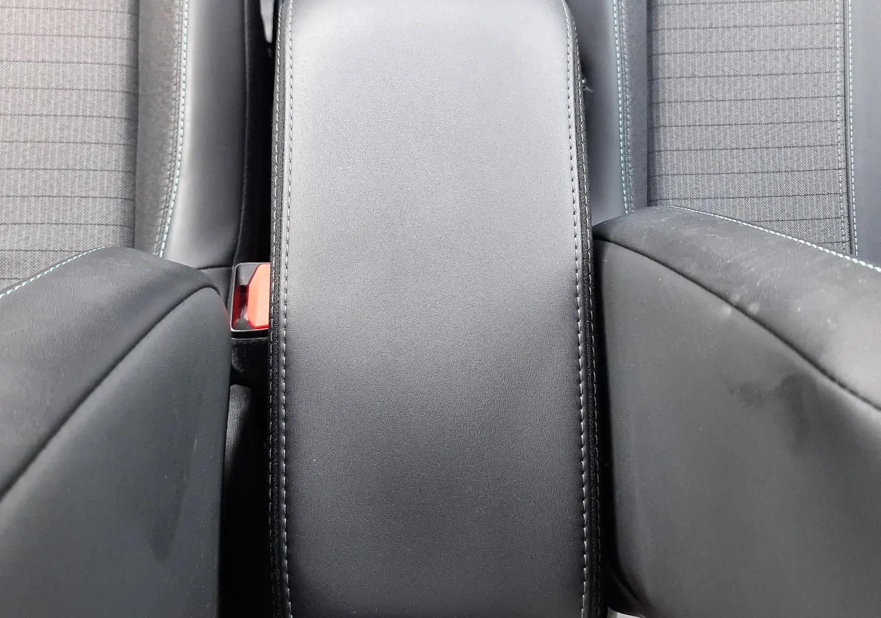 Vue plongeante sur l'accoudoir central noir et les sièges avant en tissu gris du Peugeot 2008 1.5 BlueHDi 110 Allure 2021.