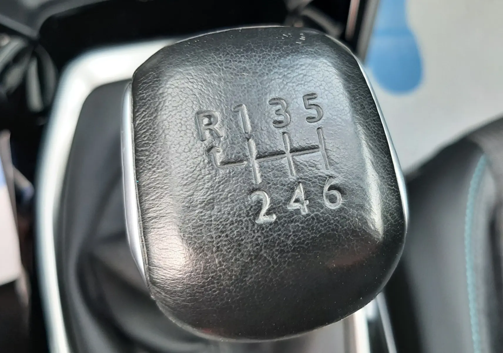 Gros plan sur le levier de vitesses manuel noir du Peugeot 2008 gris, montrant les six rapports et la marche arrière.